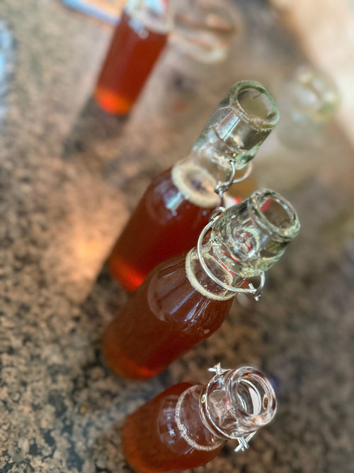 Three filled bottles of English lavender simple syrup on the counter, swing-top caps open